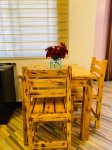 a wooden table with two chairs and a vase of flowers at Nico Garden Apartment in Dodoma