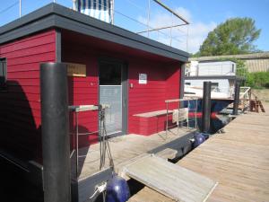 Un edificio rojo con un muelle y un barco. en Hausboot Kaddi`s Sunflower - Huus & Meer, en Burgstaaken