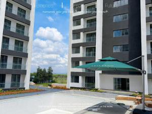 a green umbrella sitting in front of a building at Artesano Park View Furnished Apartment in Nairobi