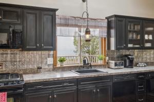a kitchen with black cabinets and a sink and a window at Coastal Comfort with Stunning Harbor Views home in Plymouth