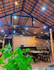 a room with tables and benches and a brick wall at Hy Viên boutique Garden & Swimming pool in Cồn Giả Viên