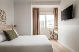 Un dormitorio con una cama, un escritorio y un televisor. en BYPILLOW Erba, en Girona