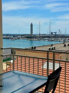 a balcony with a table and chairs and a lighthouse at ''Le Phare''grand T3 vue imprenable sur le port et la mer ! in Sète