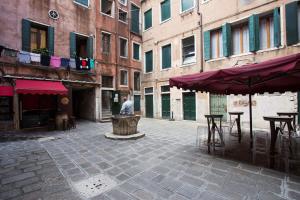 mężczyzna stojący na dziedzińcu ze stołami i parasolami w obiekcie Bartolo II - LOCAPPART w Wenecji