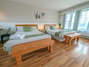two beds in a room with wooden floors and windows at Studio 17 - 2 min du Bord de l'eau Foyer & Barbecue in Sainte-Anne-de-Beaupré +40 photos