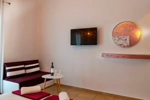 a living room with a chair and a tv on the wall at Elisabeth in Vourvourou