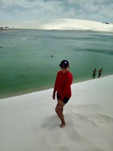 a man standing on a beach with the ocean at Tô em Casa Hospedagem in Jijoca de Jericoacoara