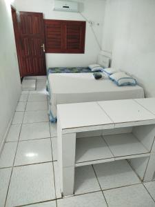 a white bedroom with a bed and a desk at Tô em Casa Hospedagem in Jijoca de Jericoacoara