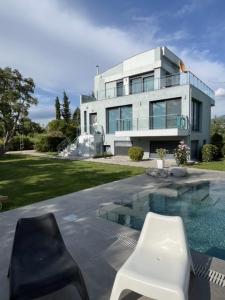 a house with a swimming pool and a white chair at Villa Linda in Thessaloniki