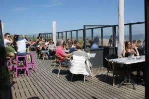 a group of people sitting at tables on a deck at Mobilheim O'Hara 6p camping Scheldeoord Baarland in Baarland