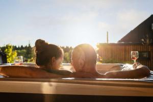 a man and woman in a bathtub with a glass of wine at TRI VODY Demänovská Dolina in Liptovský Mikuláš