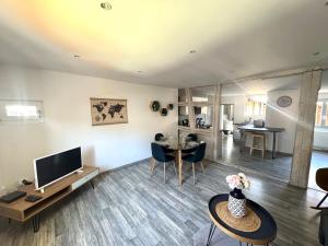 a living room with a television and a table and chairs at Au coeur de Kaysersberg-Le Cocon de Jeanne in Kaysersberg