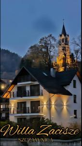 ein weißes Gebäude mit einer Kirche im Hintergrund in der Unterkunft Willa Zacisze Szczawnica Apart in Szczawnica