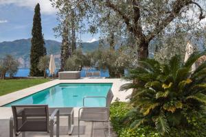 a swimming pool in a yard with chairs and trees at Villa Cipressi - Luxuri Lounge - in Malcesine