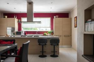 a kitchen with red walls and a counter with stools at A Casa Di Elena in Rigutino