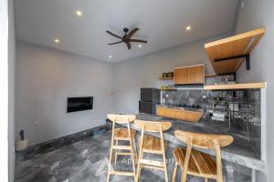 a kitchen with three bar stools and a ceiling fan at Traditional Villa Astina Cemagi in Cemagi