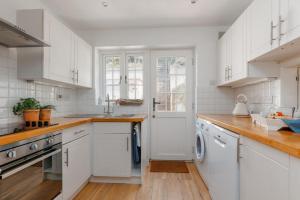 a white kitchen with wooden floors and white cabinets at Lulwind in Lulworth Cove