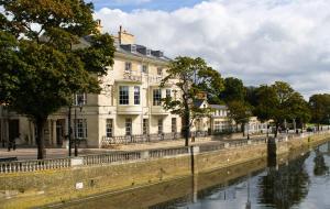 a building next to a river in front of a building at Bedford Swan Hotel and Thermal Spa in Bedford