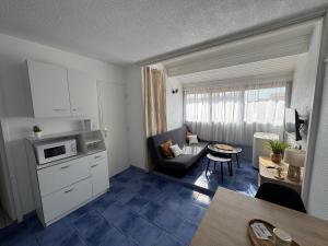 Il comprend une petite cuisine et un salon avec un canapé et une table. dans l'établissement Appartement 4 personnes à 50 m de la plage, à Narbonne