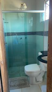 a bathroom with a toilet and a glass shower at Pousada Encontro dos Rios in Santa Bárbara