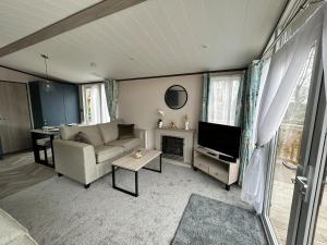 a living room with a couch and a television at Beckys Lodge in Wilberfoss