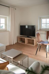 a living room with a flat screen tv and a chair at Huberhof Meran in Merano
