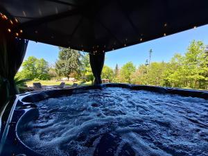 ein Whirlpool in einem Pavillon mit Bäumen im Hintergrund in der Unterkunft Château Robert in Raon-lʼÉtape