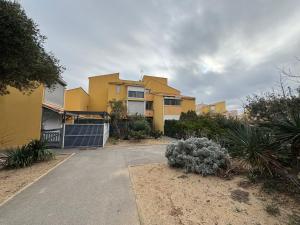 une maison jaune avec une allée devant elle dans l'établissement Appartement 4 personnes à 50 m de la plage, à Narbonne