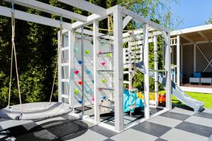 a play structure with a climbing frame and a playground at Willa Verano - Wyjątkowy Komfort Bardzo Blisko Plaży in Karwia