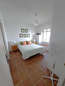 a white bedroom with a bed and a tile floor at Casa Sinclair in Gaucín +3 photos