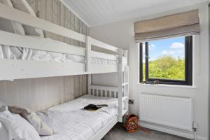 ein Schlafzimmer mit zwei Etagenbetten und einem Fenster in der Unterkunft Lilac Lodge, 22 Roadford Lake Lodges in Lifton