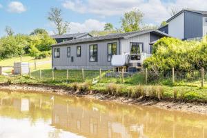 ein Haus mit einem Fluss davor in der Unterkunft Lilac Lodge, 22 Roadford Lake Lodges in Lifton