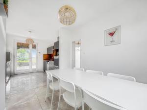 a white dining room with a white table and chairs at Le Priou - Maison Avec Grand Jardin in Buissou