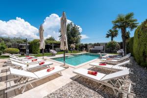 a pool with white lounge chairs and umbrellas at Evan by Briskva in Poreč