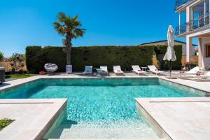 a swimming pool with chairs and a palm tree at Evan by Briskva in Poreč