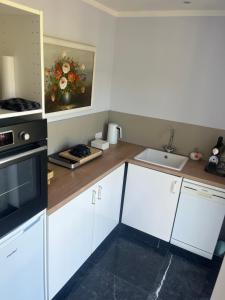 a kitchen with white cabinets and a sink at Ferienwohnung Waldseite in Bad Bentheim +16 photos
