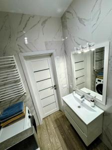 a white bathroom with a sink and a mirror at VIP apartment у центрі міста, новобудЖК Театральний,дуже простора in Rivne