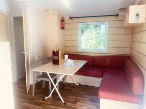 a small room with a red couch and a table at Mobil-home climatisé à 5 min de la mer, charmant in Camiers