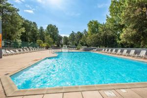 a large swimming pool with chairs at Mobil-home climatisé à 5 min de la mer, charmant in Camiers