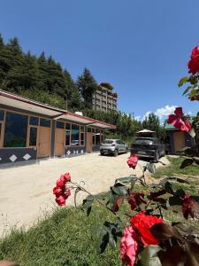 a parking lot with cars parked in front of a building at Manali Hill Stay in Manāli
