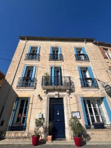 ein hohes Gebäude mit Balkonen und einer Tür in der Unterkunft Entre Midi - Maison d'Hôtes - B&B in Capestang