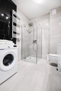 a bathroom with a washing machine and a shower at Apartament Black Sunset Resort SurfingBird Grzybowo in Grzybowo