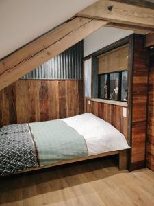 a bed in a room with a wooden wall at Appartement neuf Le Grenier d'Oscar in La Bresse