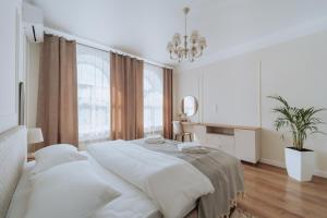 a white bedroom with a large bed and a chandelier at Central 2BR on Petru Movilă Walk to It All in Chişinău