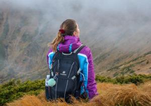 eine Frau mit einem Rucksack sitzt auf einem Hügel in der Unterkunft Apartamento Rural Dehesa de Solanillos in Mazarete + 5 Fotos