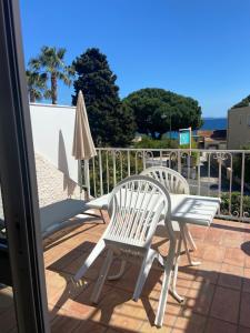 two chairs and a table and an umbrella on a patio at Les Alcyons in Le Lavandou