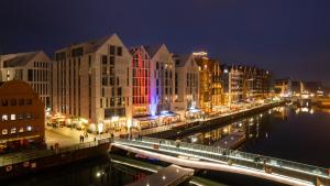 a city with buildings and a river at night at Flatbook - City Center SPA Apartments Deo Plaza Studio in Gdańsk