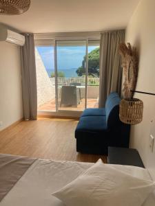 a bedroom with a bed and a couch and a balcony at Les Alcyons in Le Lavandou