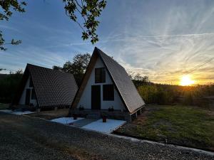 a small house with a roof with the sunset in the background at Casuțele de la răscruce in Uric