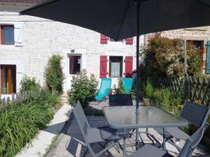 a table and chairs with an umbrella in front of a house at Aux Roses in Vrolle